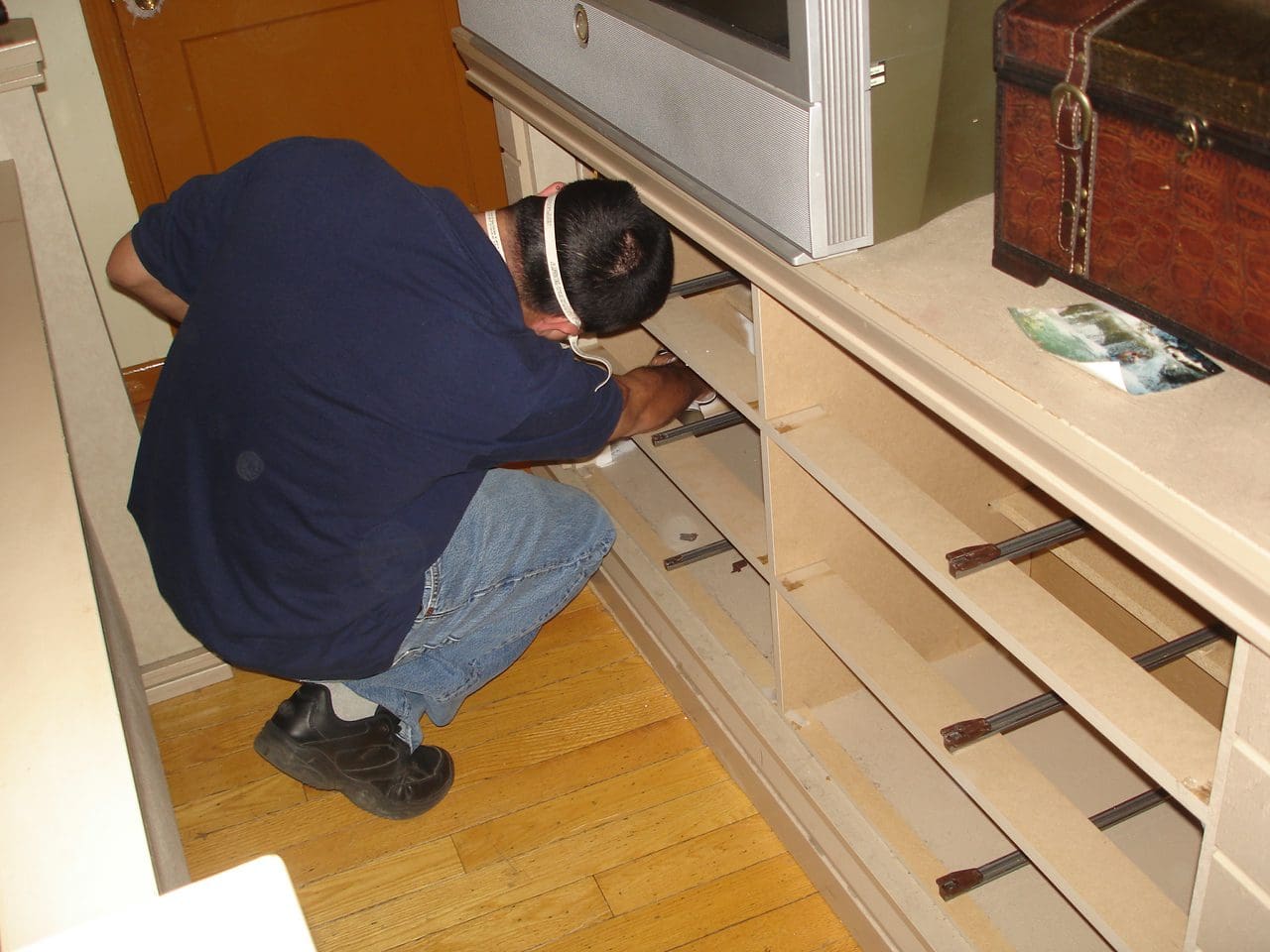 A man spreading spray under cupboard